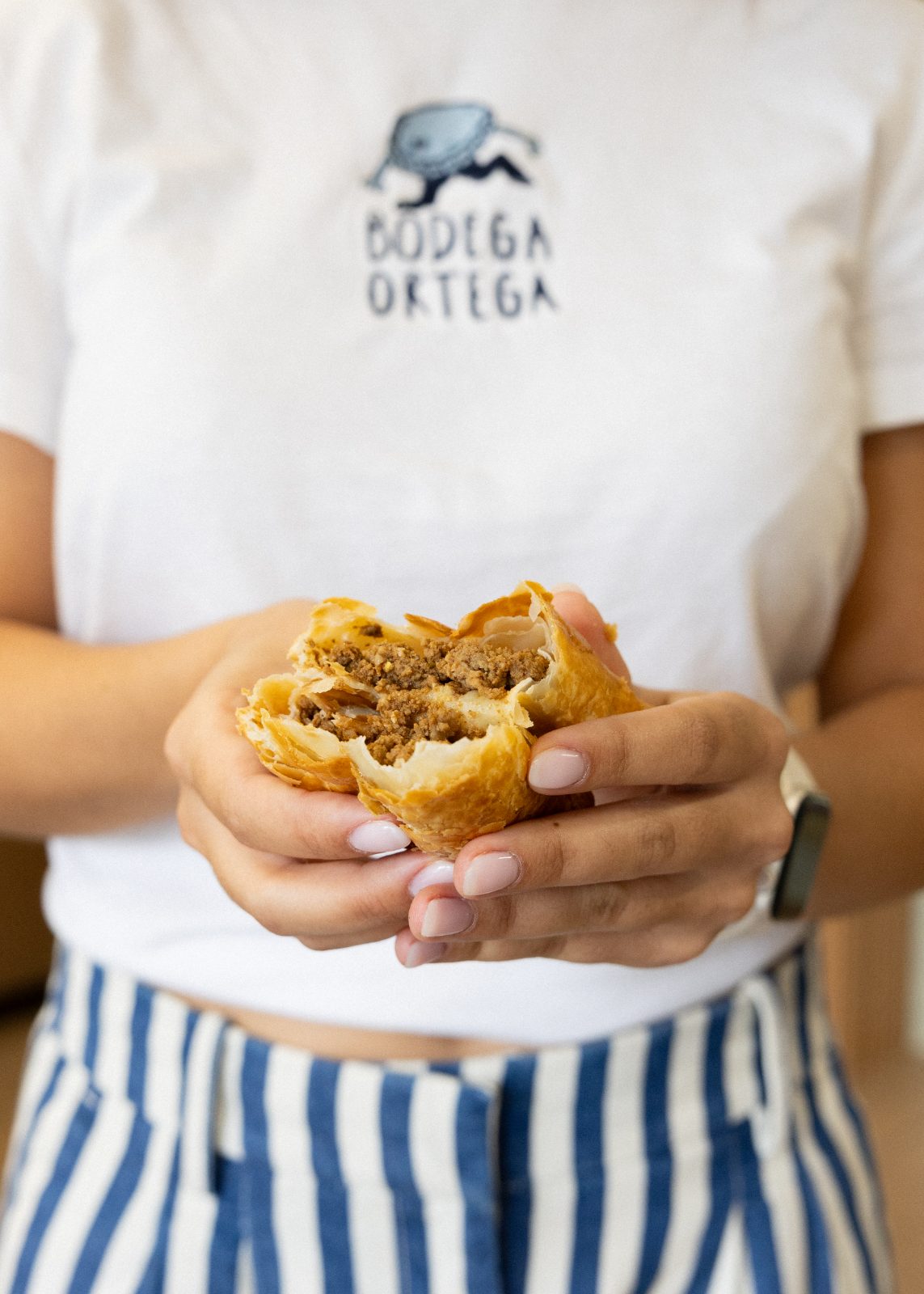 Holding a sandwich in a Bodega Ortega shirt